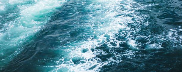 Sea or ocean waves surface texture. Abstract summer blue water background with splashes of sea foam. stock photo