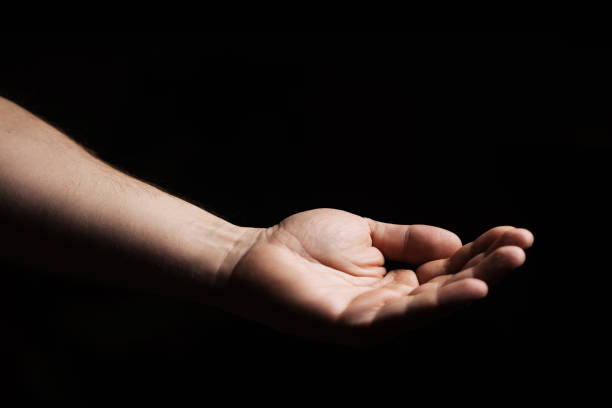 istock Male hand, palm up on a black background. Giving, asking concept. 1354180818