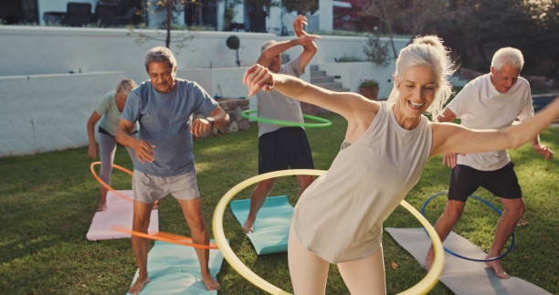 scatto di un gruppo di anziani che si allena con i cerchi hoola - yoga exercising outdoors group of people foto e immagini stock