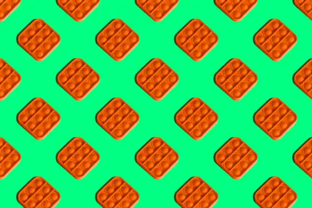 Photo of Seamless pattern from terracotta trendy popit toys on a green background. Design for children with repeating elements