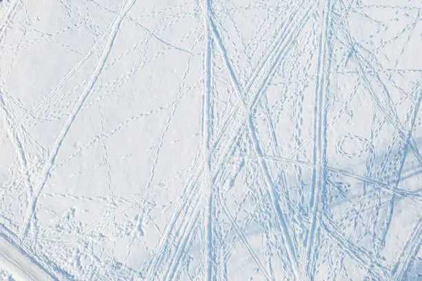 Aerial view of the ski slope covered with irregular ski tracks and footprints