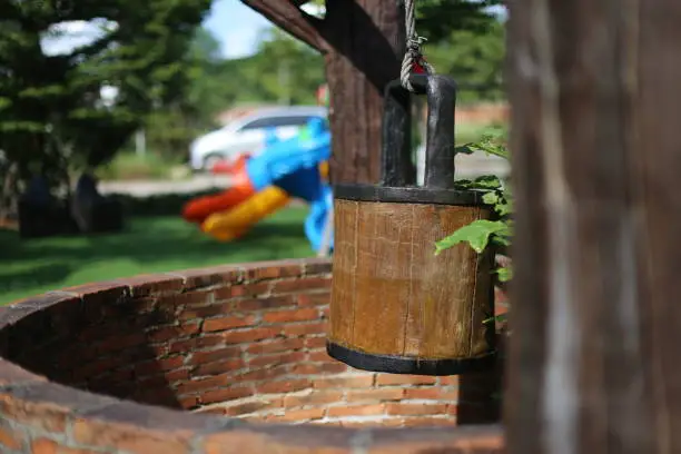 Wooden barrels hanging over the water-well. Blurred background and blurred foreground.