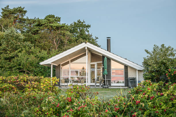 una casa de verano con una fachada de vidrio en un pequeño césped detrás de unos grandes escaramujos - denmark house cottage rural scene fotografías e imágenes de stock