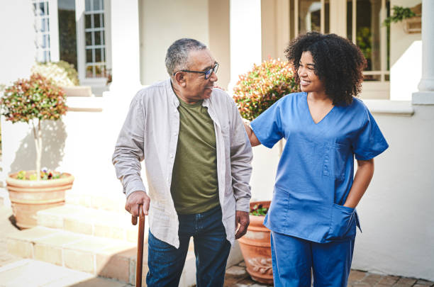 istock Shot of a senior man using a walking stick outside while his nurse helps him 1354184053