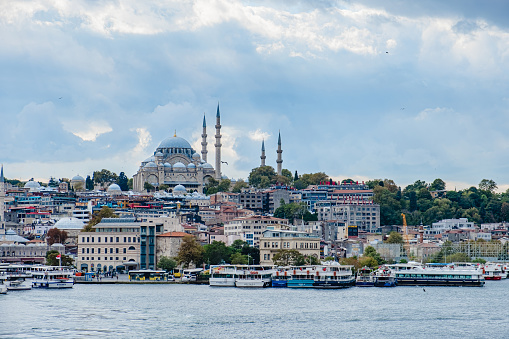 Istanbul, Turkey - October 1, 2021. Istanbul cityscape with boats and Suleymaniye Mosque. Eminonu Ferryboat docks facing the mouth of the Golden Horn Bay.