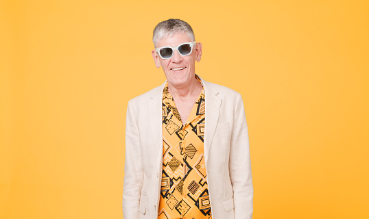 Shot of a senior man standing alone in the studio against a yellow background