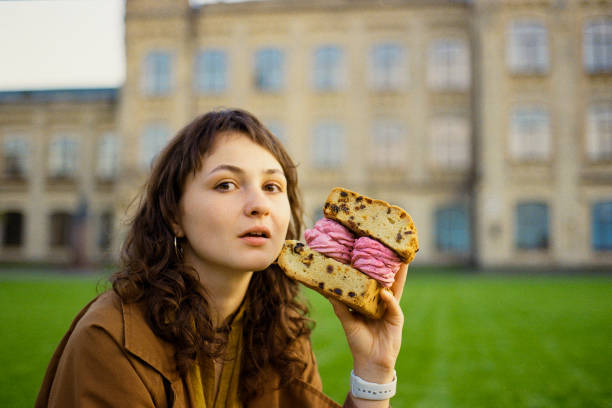 woman eating huge sandwich made of biscuit and marshmallow - eating sandwich emotional stress food imagens e fotografias de stock