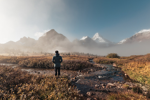 Traveler man standing and looking the mount Assiniboine in foggy on autumn forest at provincial park, Canada