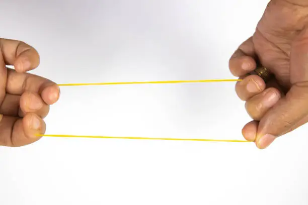 Front view of stretching a rubber band by female hand on a white background