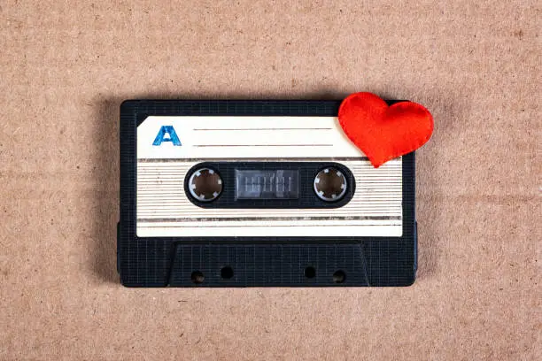 Old Audio Cassette with a Red Heart on the Cardboard Background closeup