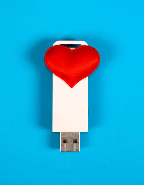 USB Flash Drive with a Heart Shape on the Paper Background closeup