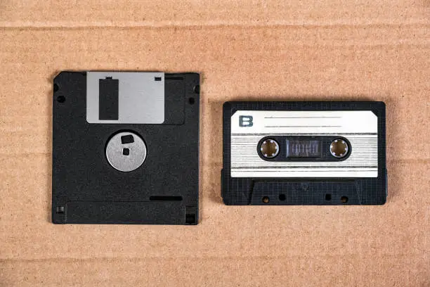 Floppy Disk Drive and Old Audio Cassette on the Cardboard Background closeup