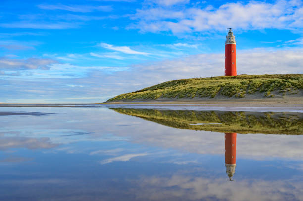 Lighthouse at the Wadden island Texel in the dunes during a calm autumn afternoon with reflections on the North Sea beach. The Eierland lighthouse is located at the North point of the island.