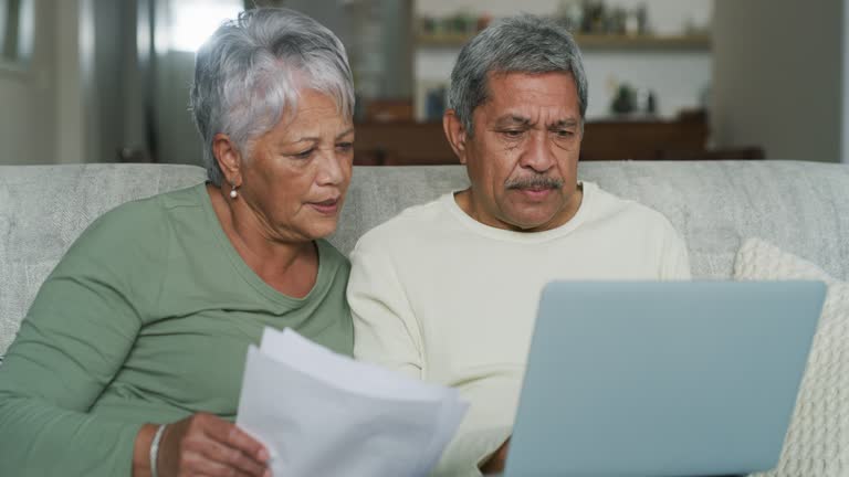 4k video footage of a senior couple sitting on the sofa and feeling stressed while calculating their finances