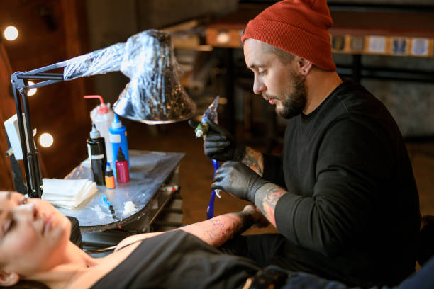 istock Professional male bearded caucasian tattoo master is working in cozy atmospheric studio 1354192528