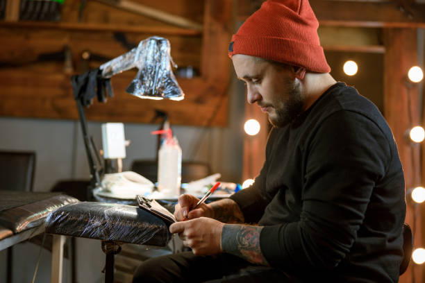 istock Professional male bearded caucasian tattoo master is working in cozy atmospheric studio 1354192529
