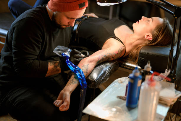 istock Professional male bearded caucasian tattoo master is working in cozy atmospheric studio 1354192533