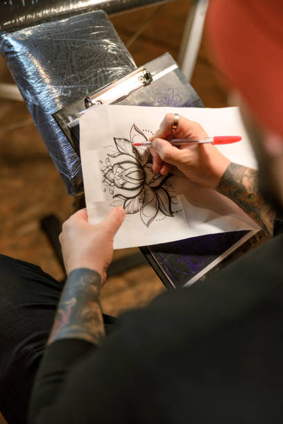 Professional male bearded caucasian tattoo master is working in cozy atmospheric studio