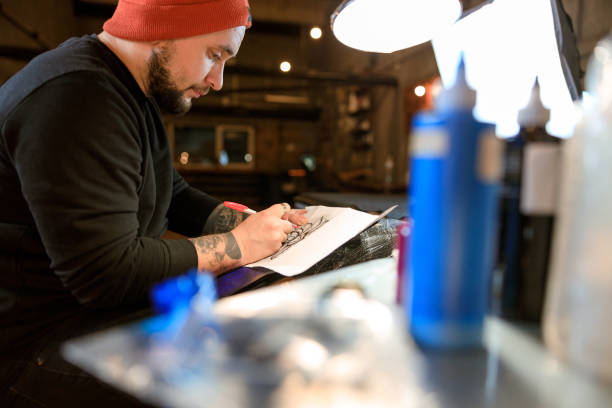istock Professional male bearded caucasian tattoo master is working in cozy atmospheric studio 1354192548