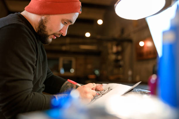 istock Professional male bearded caucasian tattoo master is working in cozy atmospheric studio 1354192550