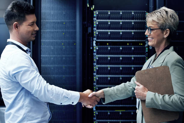 istock Shot of two technicians shaking hands while working together in a server room 1354192773