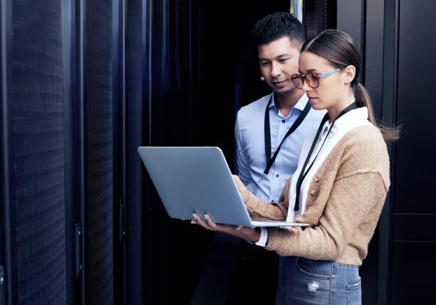 plan de deux techniciens travaillant ensemble dans une salle de serveurs - computer network photos et images de collection