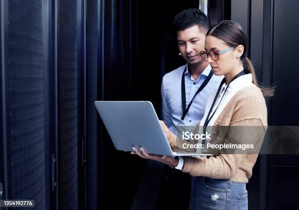 Shot Of Two Technicians Working Together In A Server Room Stock Photo - Download Image Now