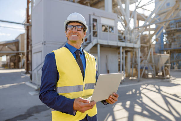 istock Cheerful man with laptop standing outdoors at factory 1354192841