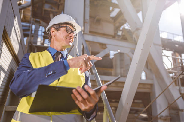 istock Male engineer with documents pointing at something at factory 1354192869