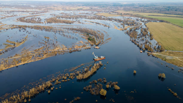 istock Floating crane on the river. Dredging crane working near shore. Conservation river flow. Nature, river, sky, clouds. 1354192990