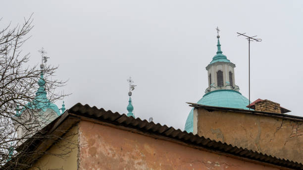 Catholic dom with cross viewed through television aerial antennae and apartment rooftops.