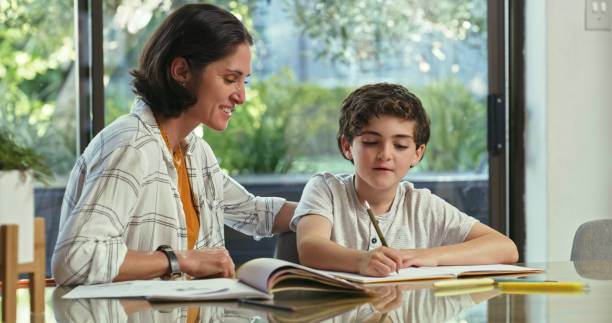istock Shot of a woman sitting with her son while he does his homework 1354194267