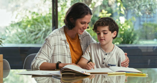 istock Shot of a woman sitting with her son while he does his homework 1354194269