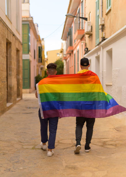 istock Men with rainbow flag walking in alley 1354194788