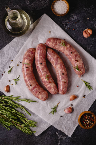 istock Raw sausages and ingredients for cooking on a black stone table 1354195938