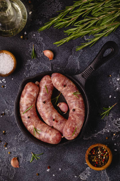 istock Raw sausages and ingredients for cooking on a black stone table 1354195946