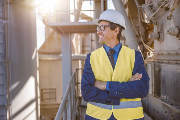 istock Cheerful male engineer standing at manufacturing plant 1354196076