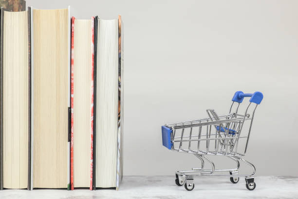 istock Shopping trolley and several paper books standing upright. Space for text on top 1354197324