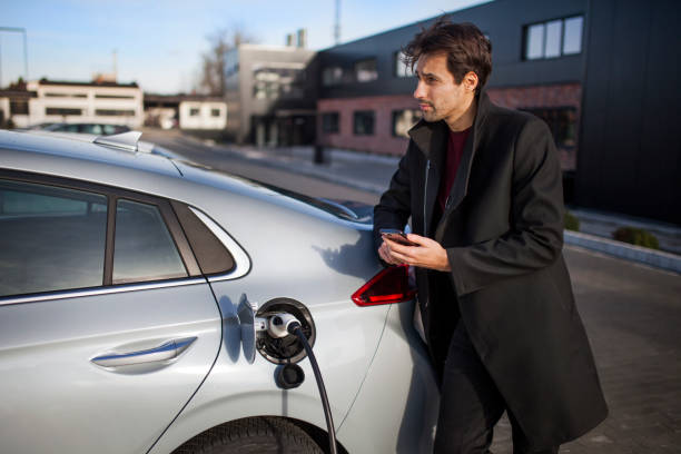 istock Young man on a parking lot, charging his electric car 1354201749