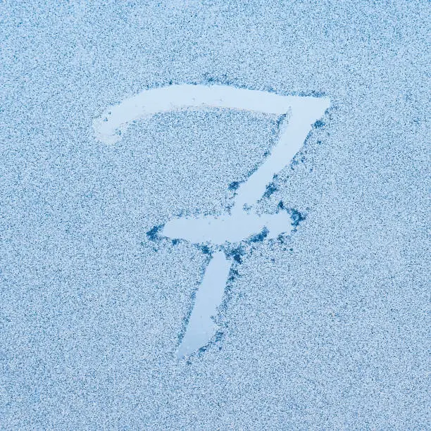 Photo of Number 7, written on glass with frost in the frost in winter, close up