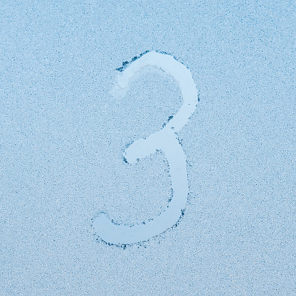 Number 3, written on glass with frost in the frost in winter, close up.