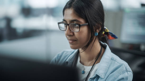 istock Diverse Office: Portrait of Confident Indian IT Programmer Working on Desktop Computer. Female Specialist Wearing Glasses Create Innovative Software. Professional Engineer Develop Inspirational App 1354205211