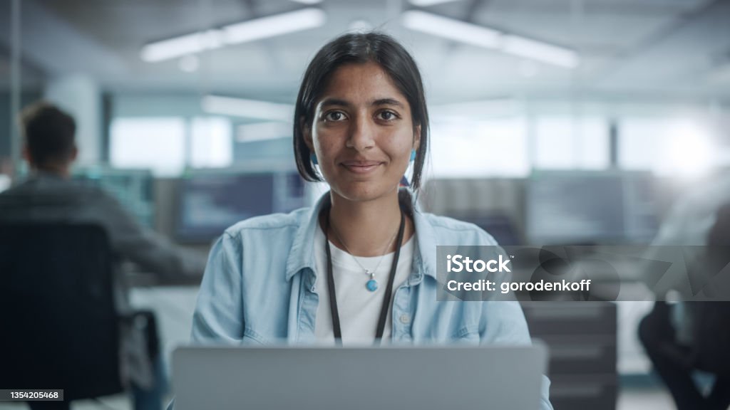 Diverse Office: Portrait of Beautiful Indian IT Programmer Working on Desktop Computer, Smiling and Looking at Camera Kindly. Female Software Engineer Creating Innovative App, Program, Video Game Computer Programmer Stock Photo
