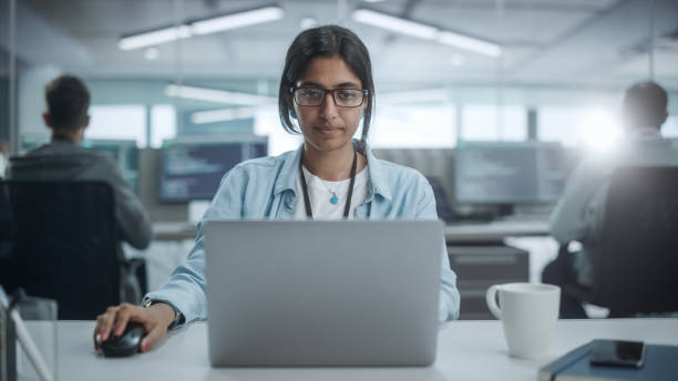 istock Diverse Office: Portrait of Smiling Indian IT Programmer Working on Desktop Computer. Female Specialist Create Innovative Software. Professional Engineer Develop App. 1354205471