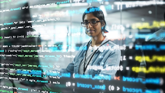 Diverse Office: Retrato de un programador de TI indio confiado que trabaja en una computadora de escritorio. Especialista profesional femenina desarrolla software innovador. Grabado con efectos visuales de código en ejecución. photo