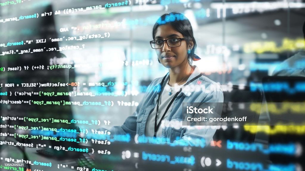 Diverse Office: Portrait of Confident Indian IT Programmer Working on Desktop Computer. Professional Female Specialist Develop Innovative Software. Shot with Visual Effects of Running Code. Technology Stock Photo