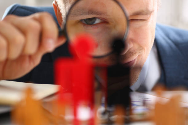 istock Man in suit holding loupe at workplace 1354206220