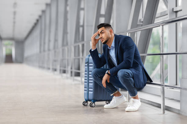 istock Missed Flight. Upset Middle Eastern Man Sitting Next To Suitcase At Airport 1354206453
