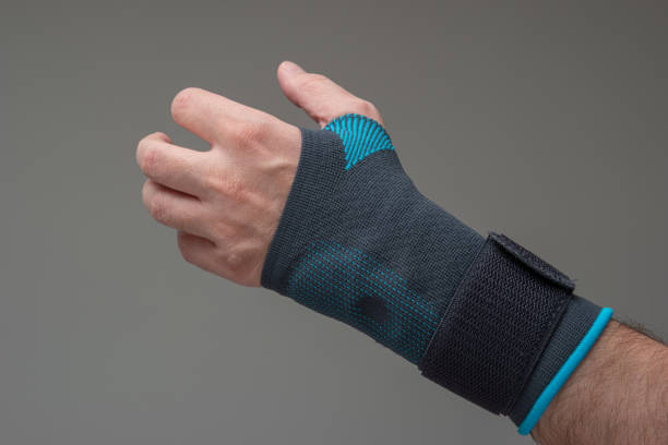 Velcro wrist stabilizer cast worn by Caucasian male hand. A blue split brace meant to aid Carpel Tunnel syndrome. Close up studio shot, isolated on gray background stock photo