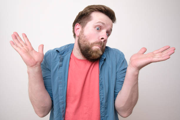 istock Man spreads arms in bewilderment, according to his expression it is not clear whether he is guilty or not. White background. 1354209607